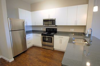 A kitchen with a refrigerator, microwave, oven, sink and cabinets.